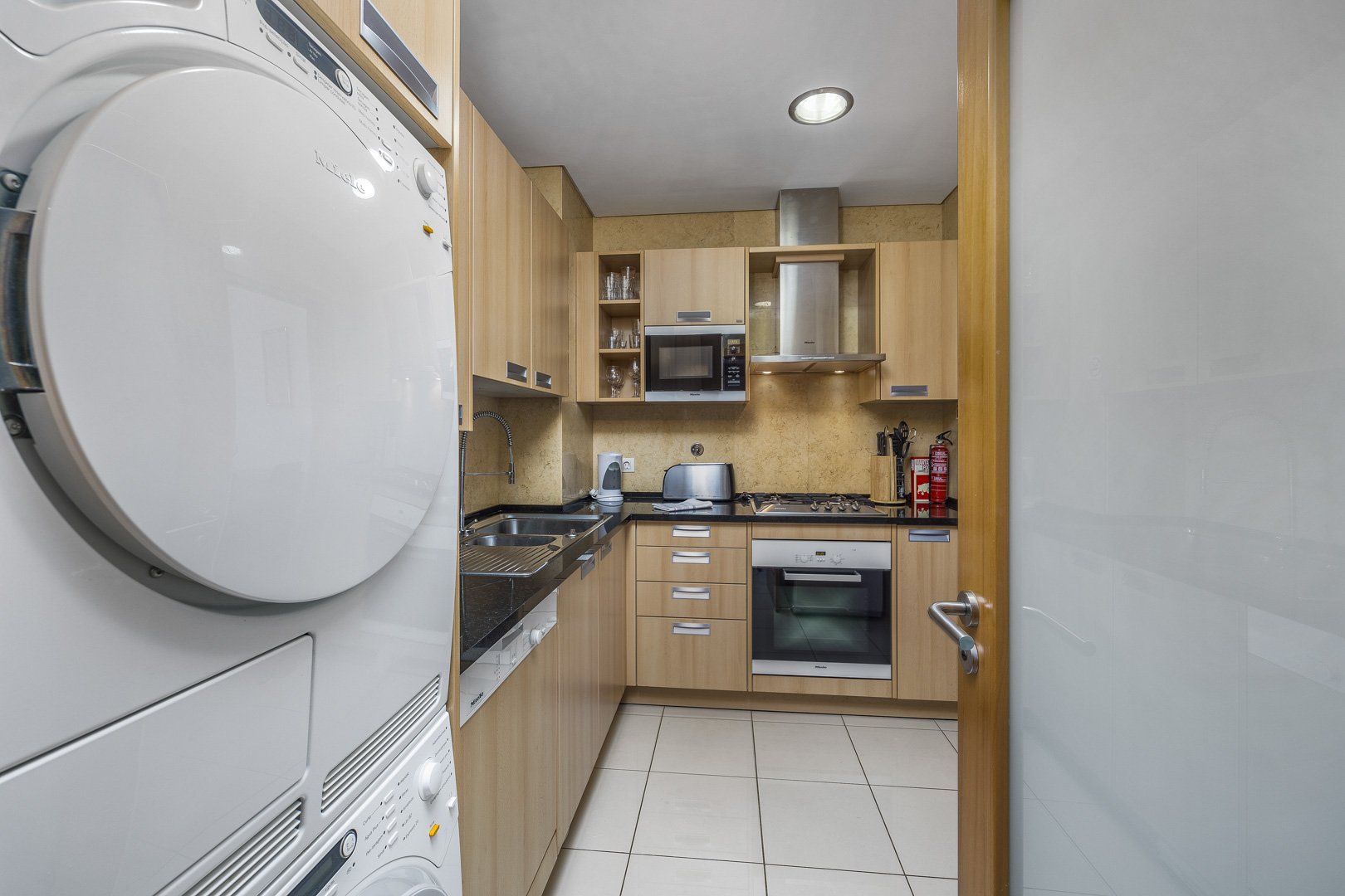 Kitchen with stacked washer-dryer and view through to the hallway
