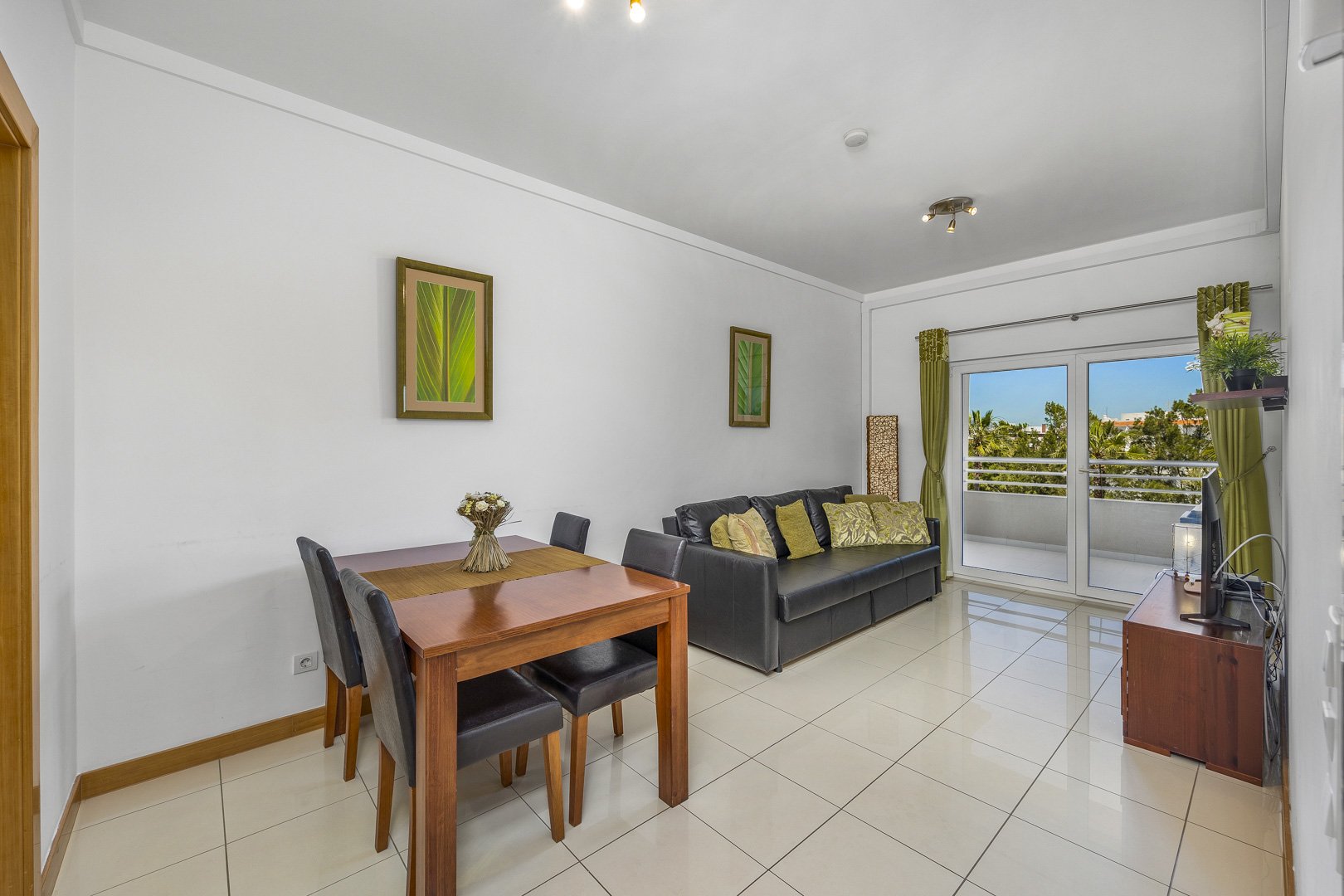 Living and dining area with dining table, sofa, and balcony doors