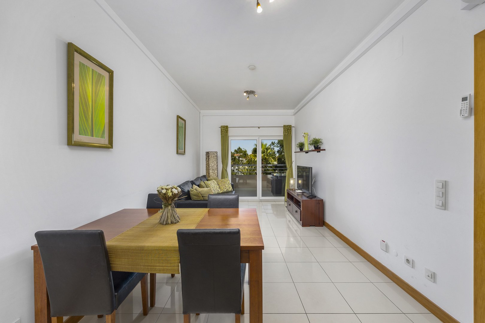 Living and dining area with dining table, sofa, and balcony access