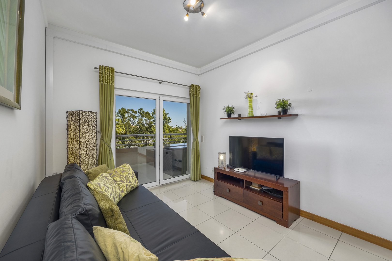 Living room with sofa, TV, and balcony access