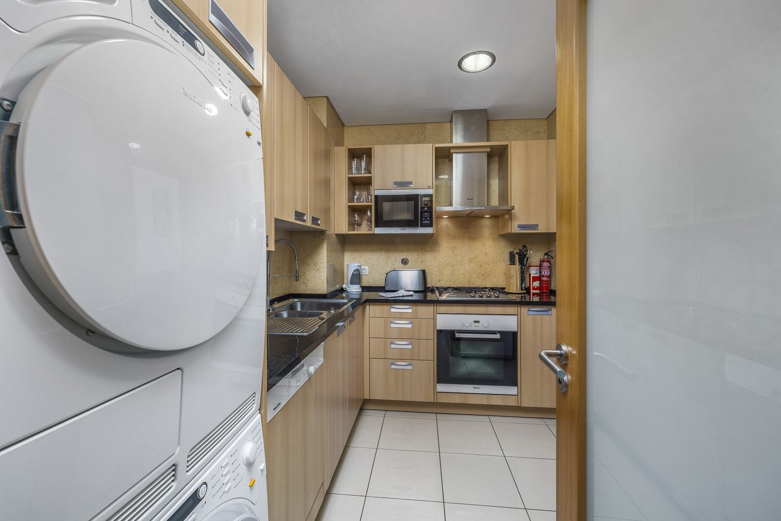 Kitchen with stacked washer-dryer and view through to the hallway