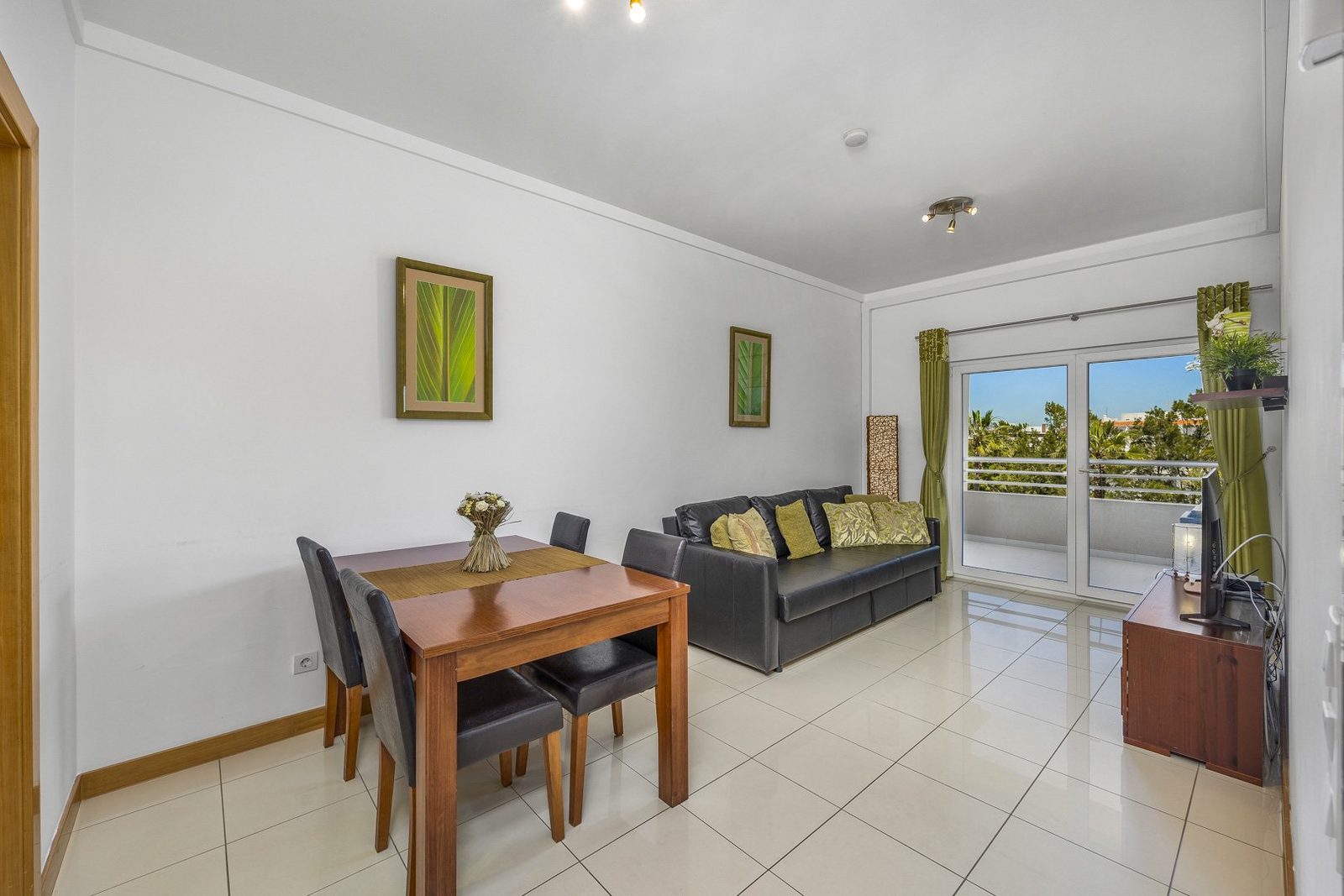 Living and dining area with dining table, sofa, and balcony doors