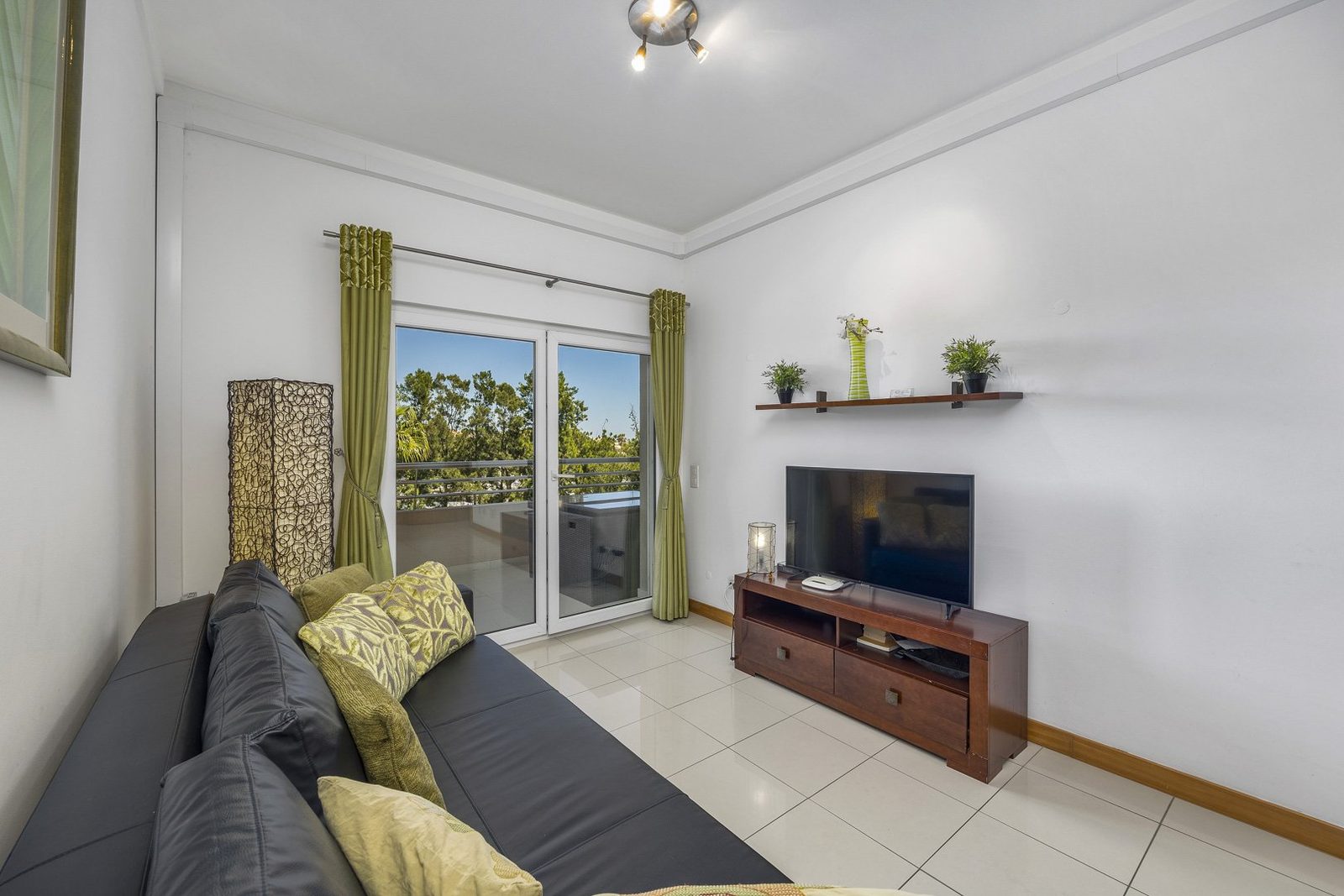 Living room with sofa, TV, and balcony access