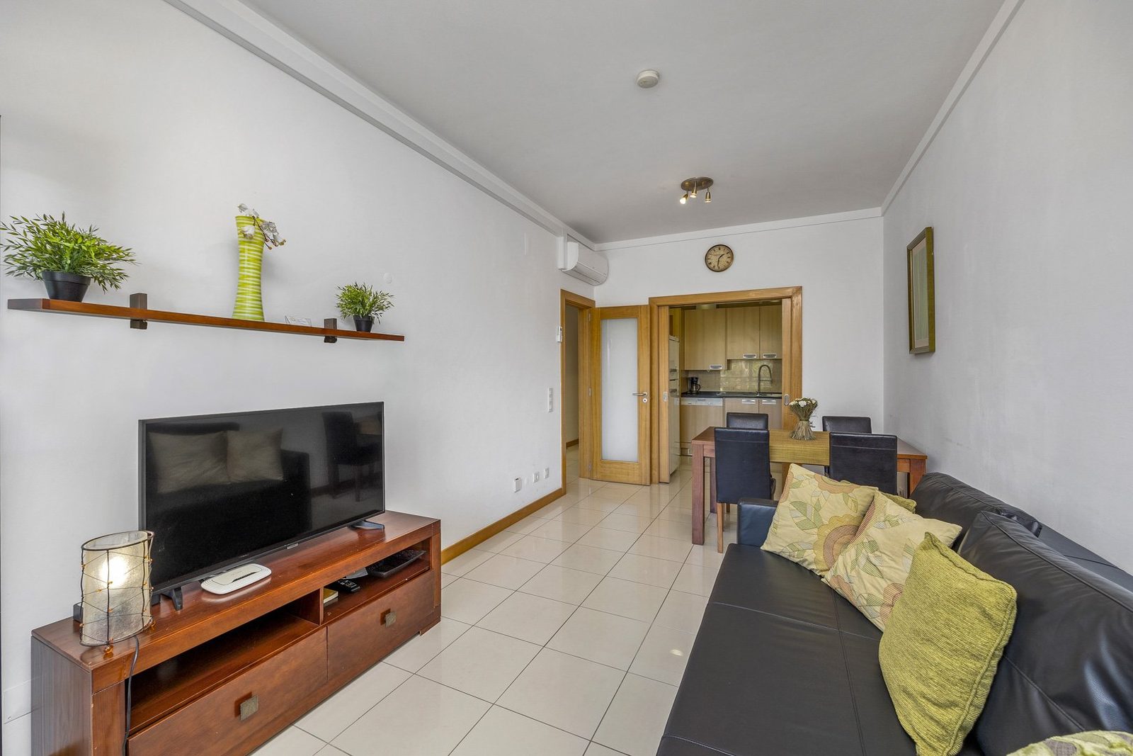 Living room with TV stand, sofa, and open kitchen doorway