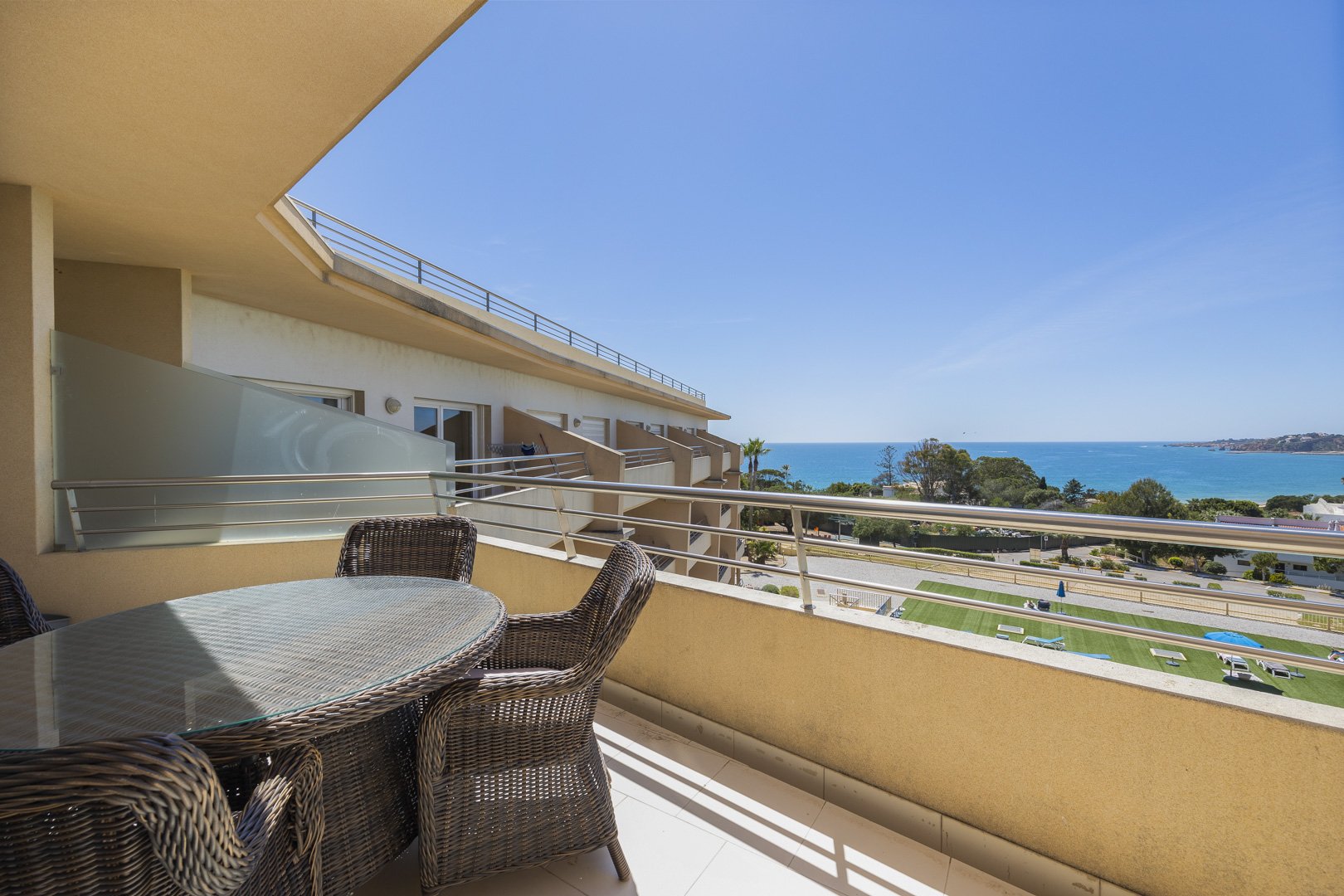 Balcony seating area with shade sail and elevated sea view