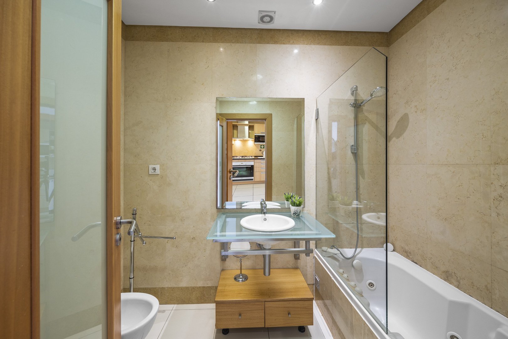 Bathroom with bathtub, glass shower screen, and vanity unit