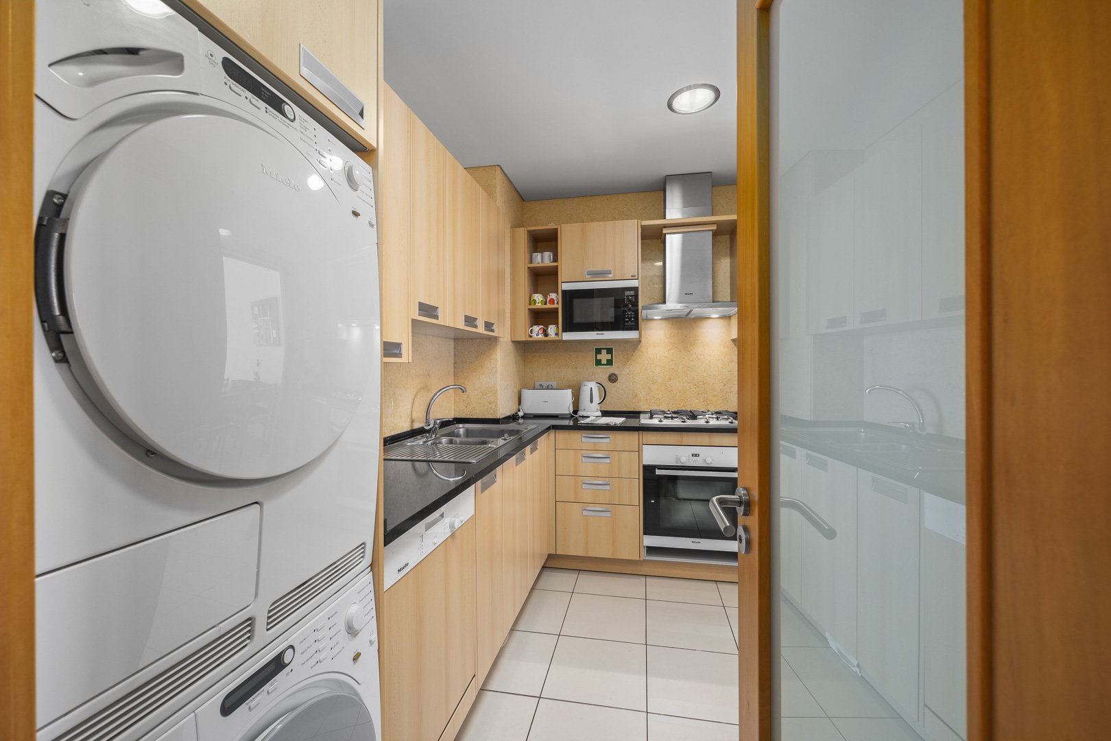 Kitchen with stacked washer-dryer and view through to the hallway
