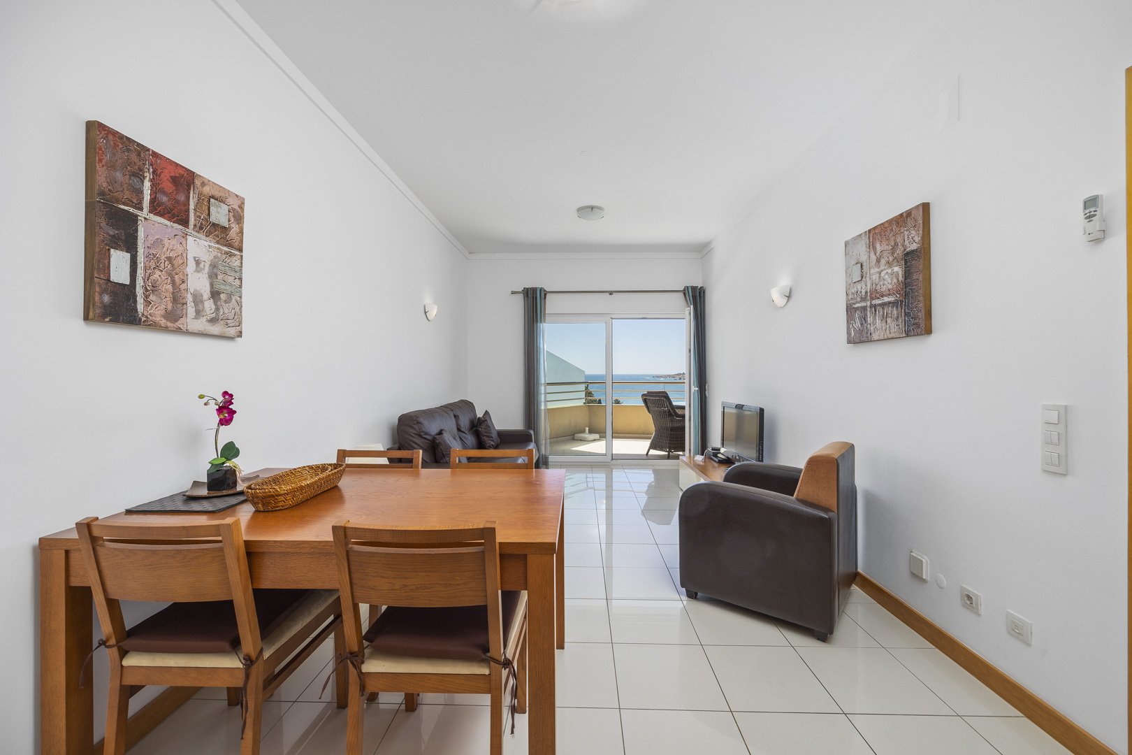 Living and dining area with dining table, sofa, and sea view balcony