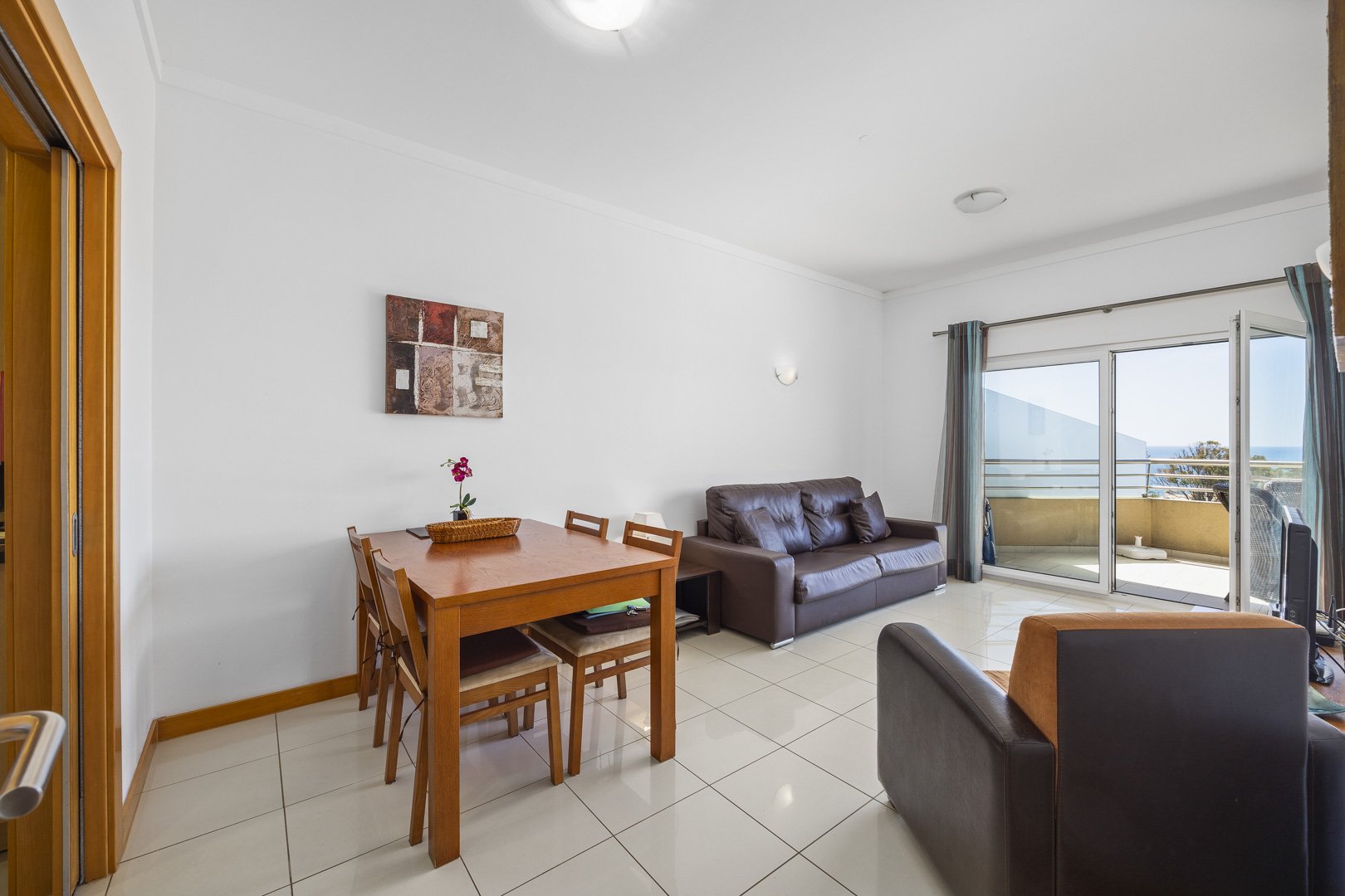 Living room with sofa, dining table, and sea view balcony doors