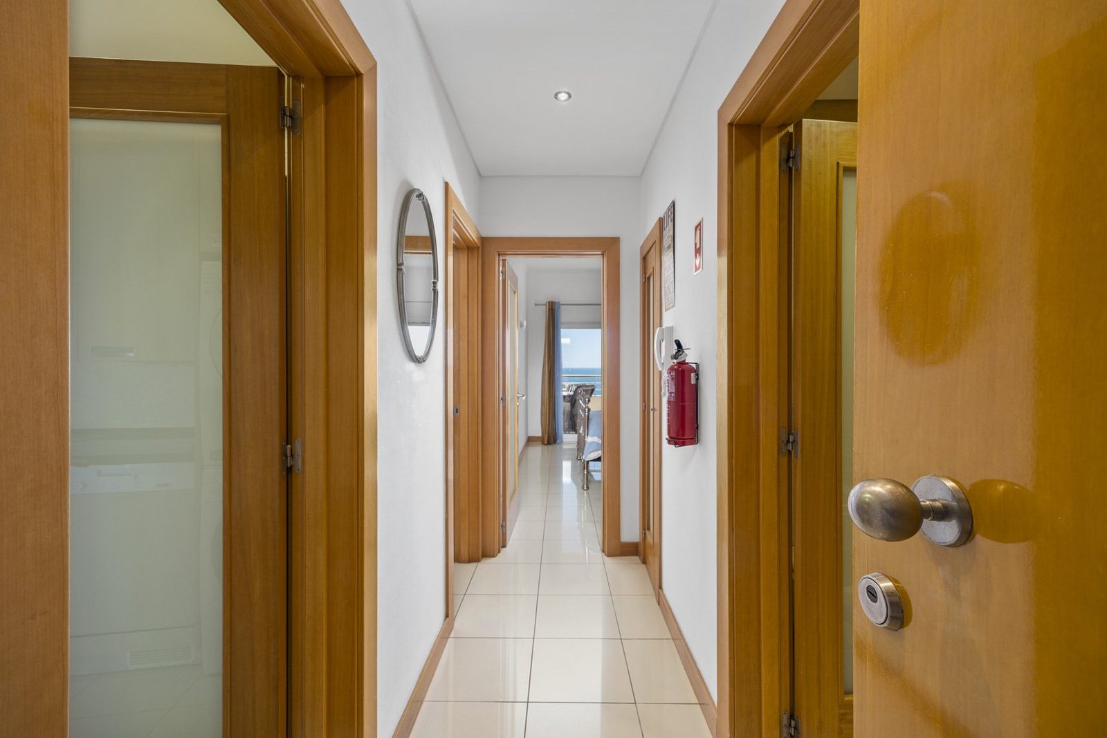 Hallway with mirror and doors leading to the bedrooms and kitchen
