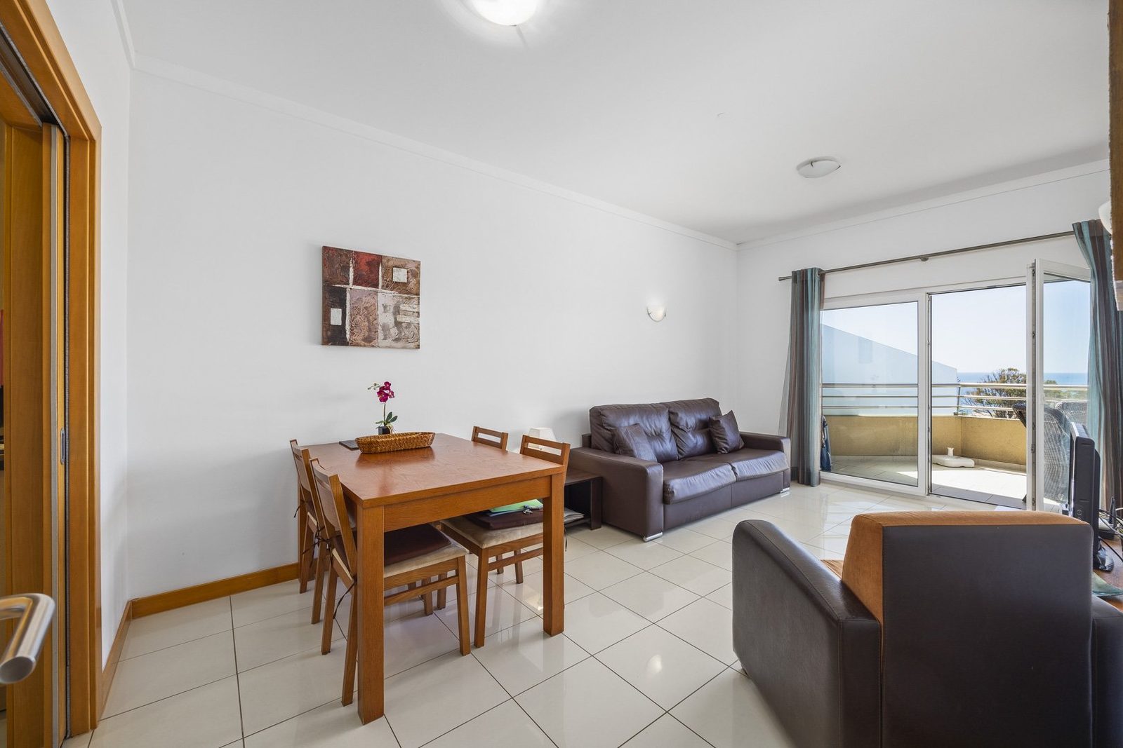 Living room with sofa, dining table, and sea view balcony doors