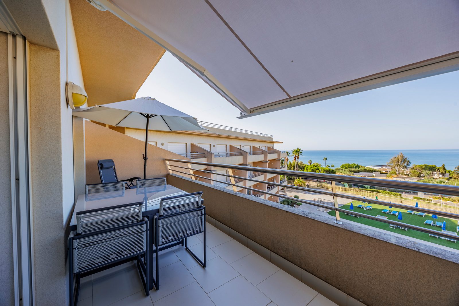 Balcony with dining table, parasol, and sea view