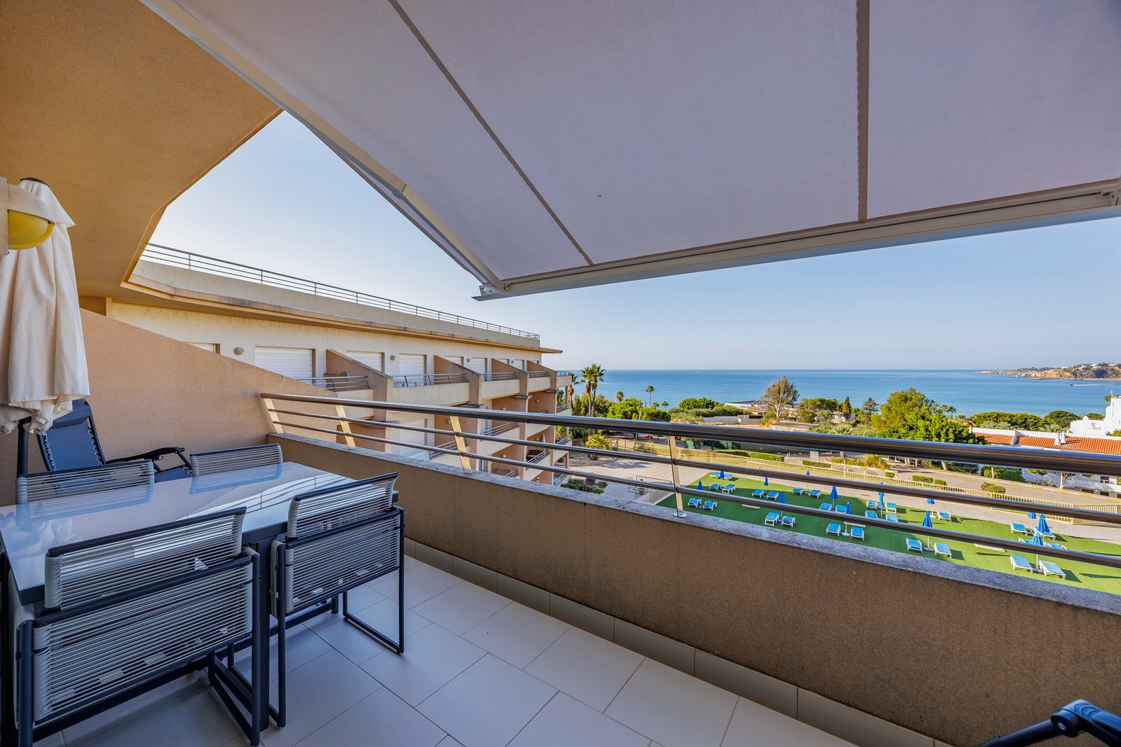 Balcony dining table under the awning, with pool and sea view