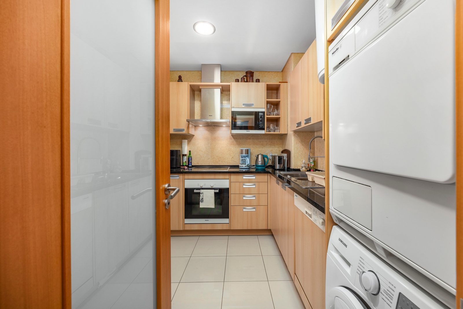 Kitchen seen through the sliding door, with stacked washer and dryer