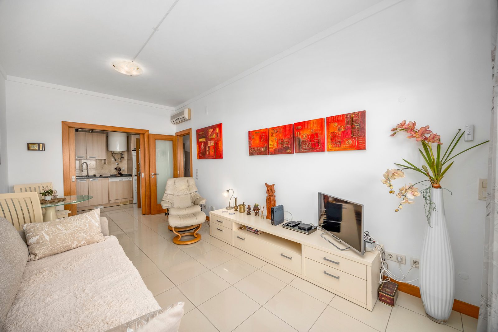 Living room with armchair, TV unit, and view through to the kitchen