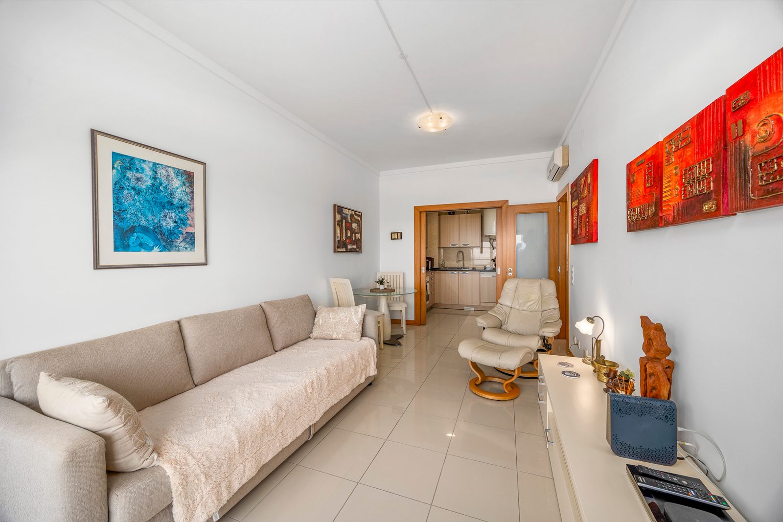 Living room with sofa and armchair, looking through to the kitchen