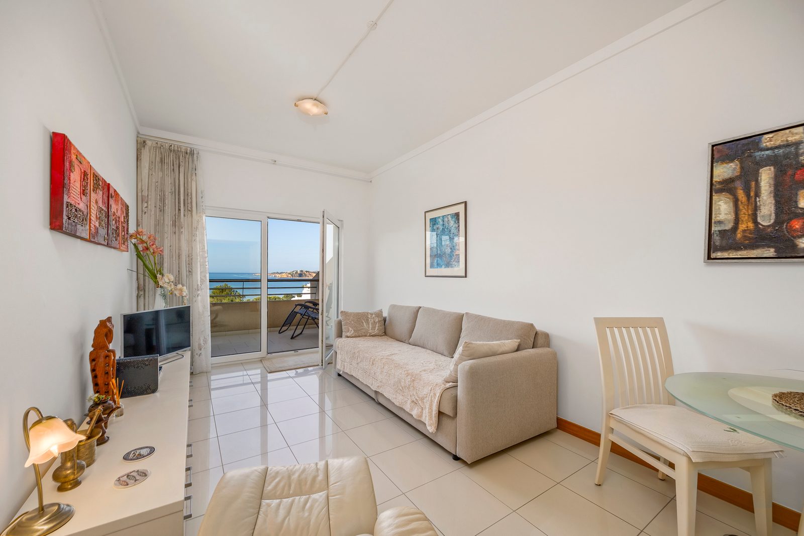 Living room with sofa, TV, and balcony doors with sea view