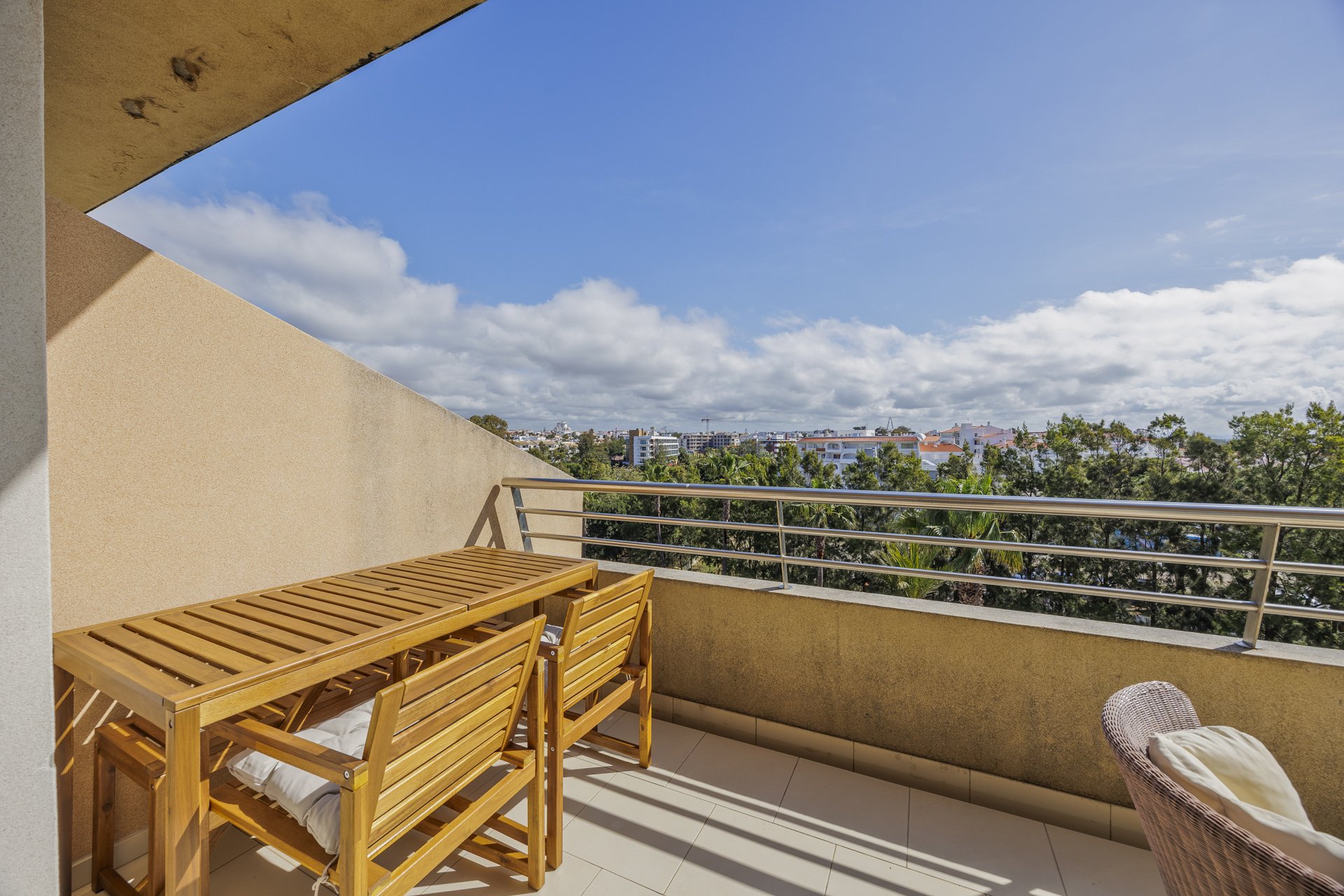 Balcony seating area with wooden table and coastal view