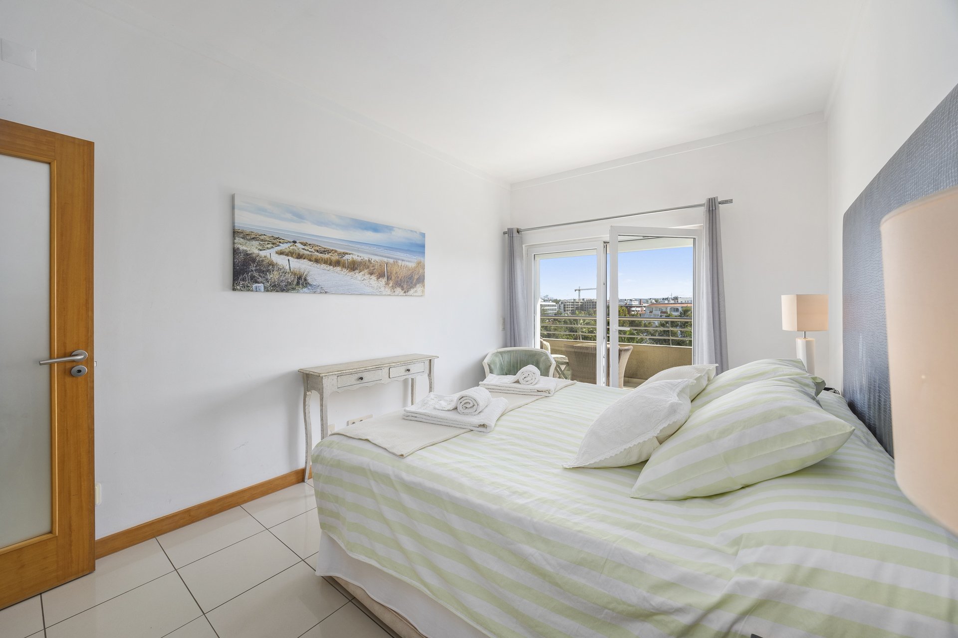 Bedroom with striped bedding, artwork, and balcony access