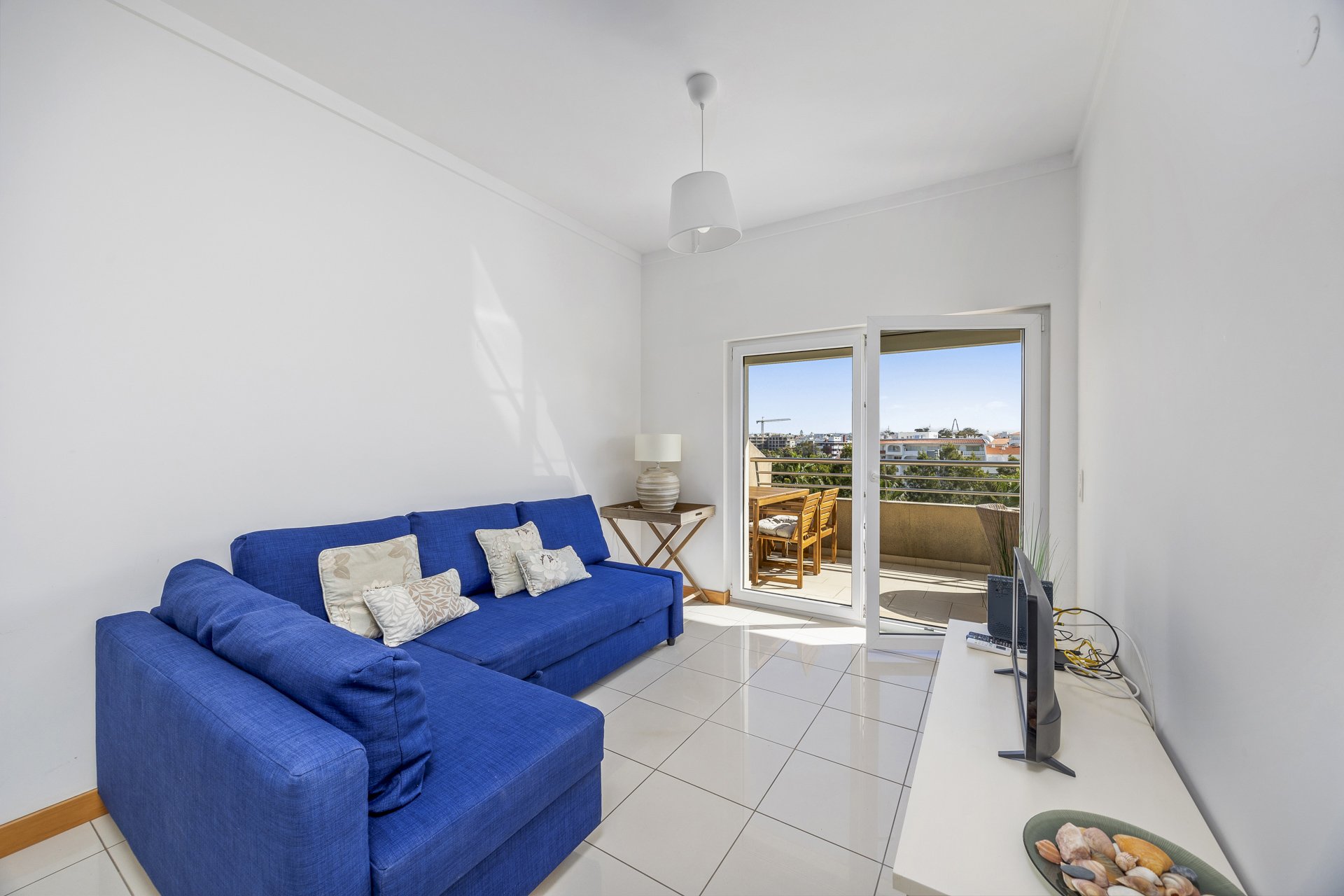 Living room with sofa, TV, and balcony access
