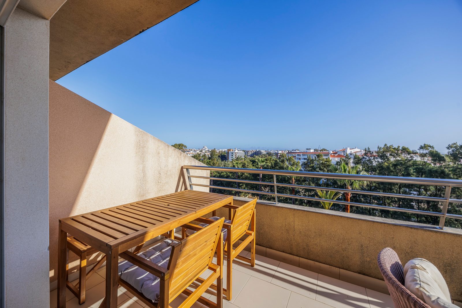 Balcony dining table and chairs with a view over the treetops and the sea
