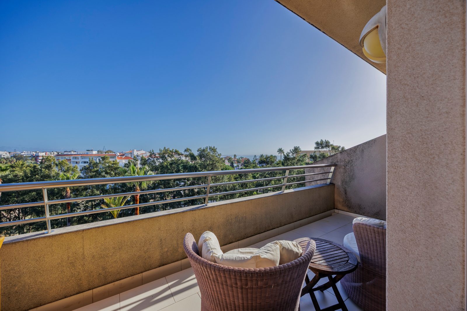 Balcony seating area with wicker armchairs and a view over the town towards the sea