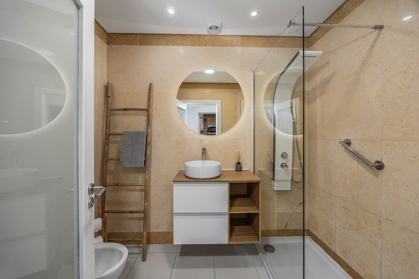 Bathroom with walk-in shower, round mirror, and washbasin