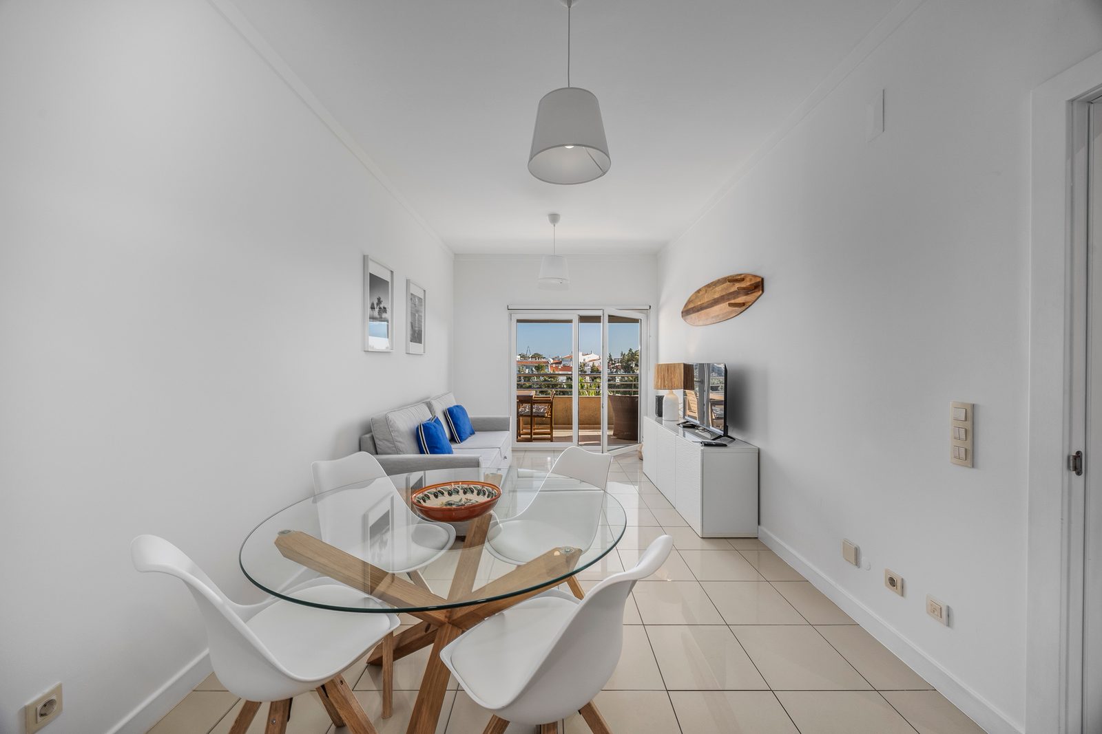 Dining table and sofa with surfboard decor and a view through to the balcony