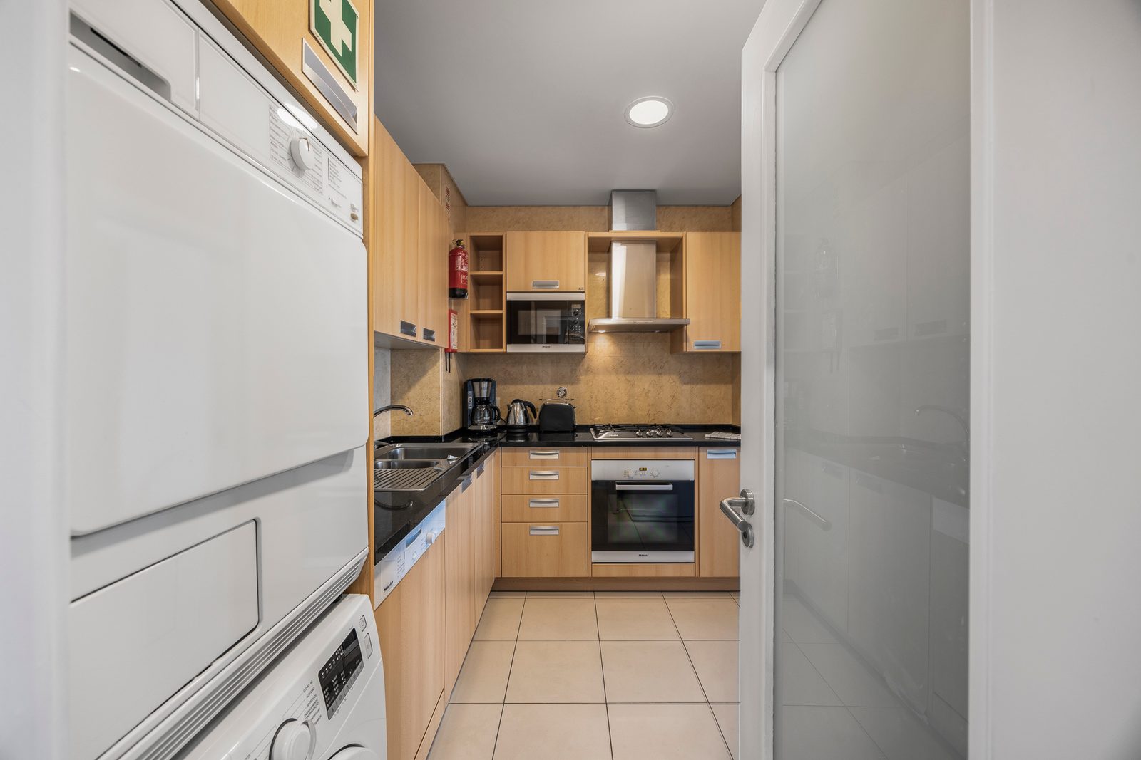 Kitchen with stacked washer-dryer, hob, and oven