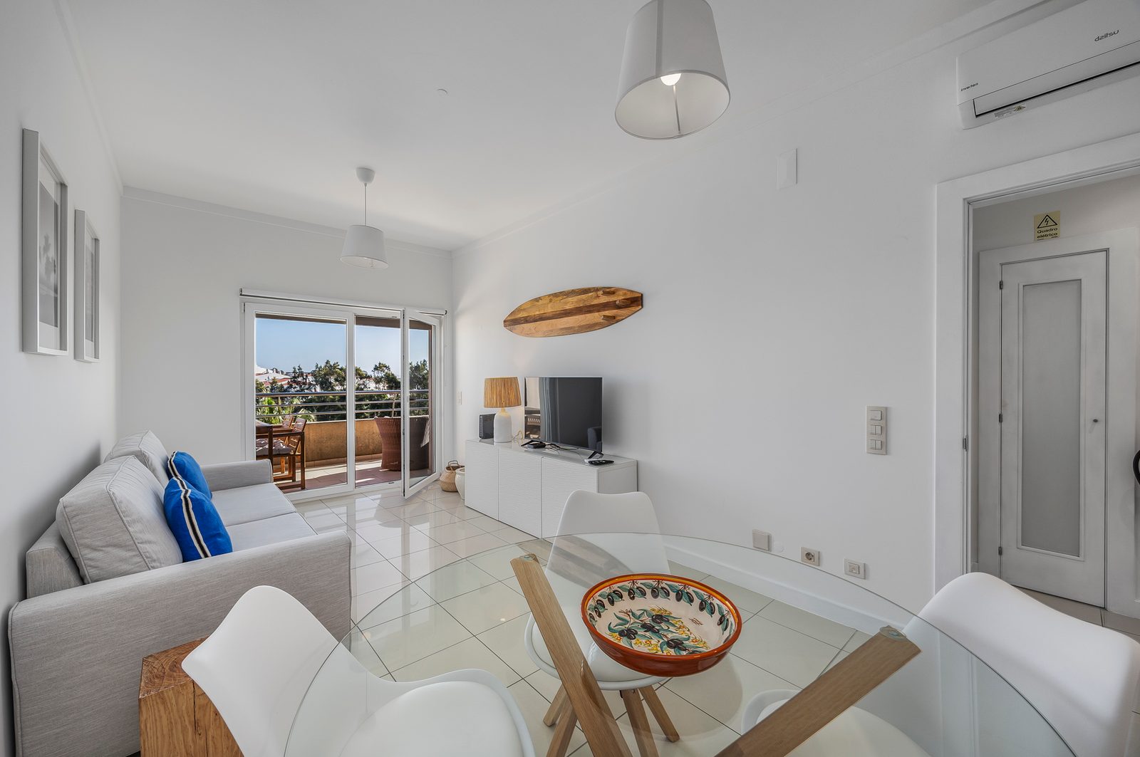 Living room with sofa, TV, glass dining table, and balcony doors