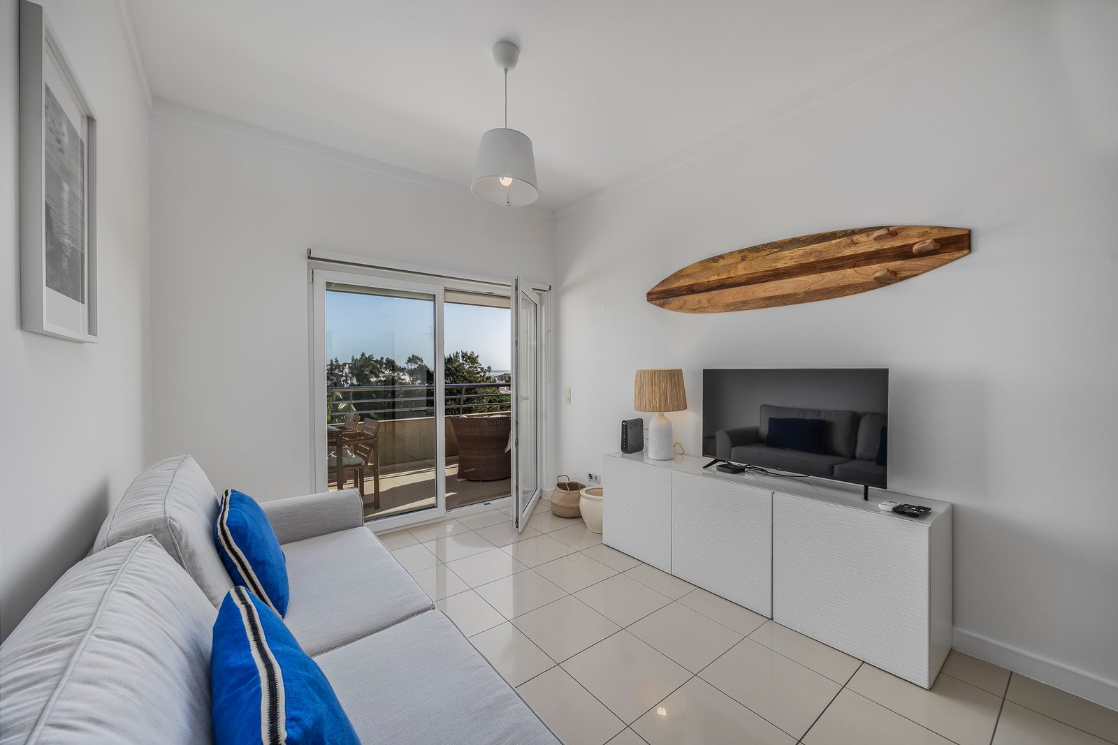 Living room with sofa, TV unit, and balcony access