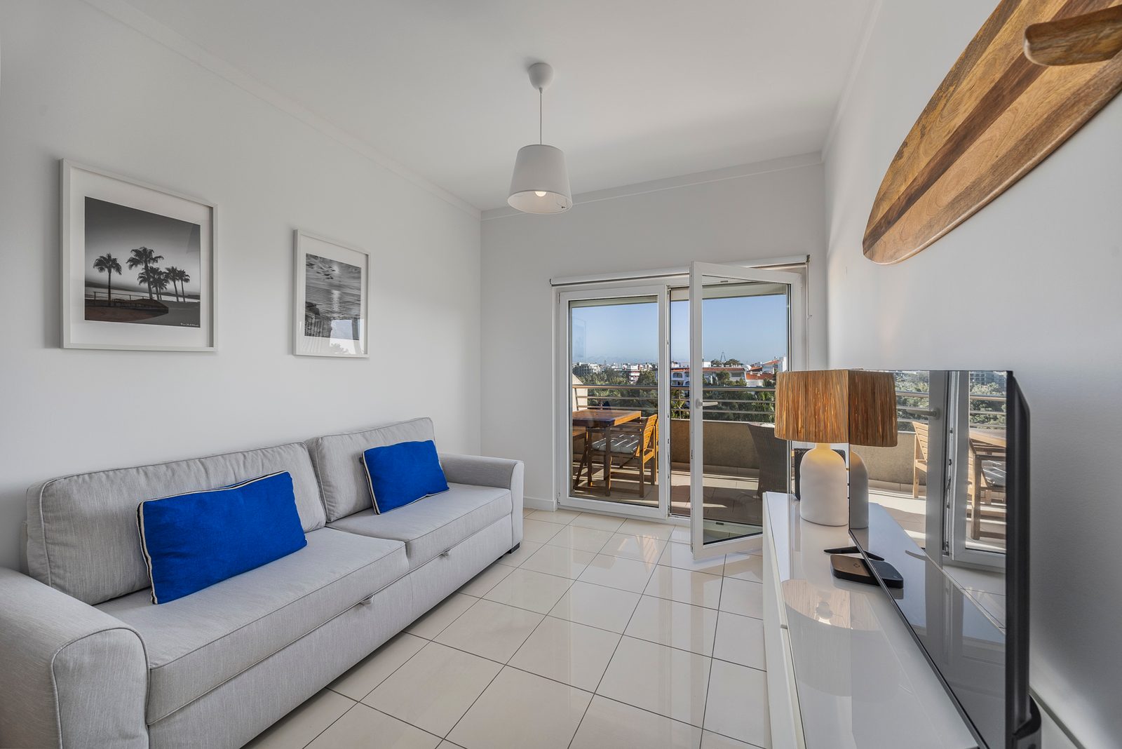 Sofa with blue cushions, TV, and balcony doors onto the terrace