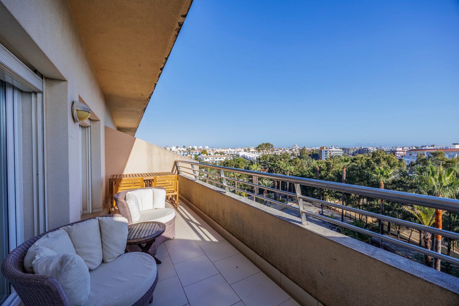 Wide balcony with wicker lounge chairs and a view across Albufeira