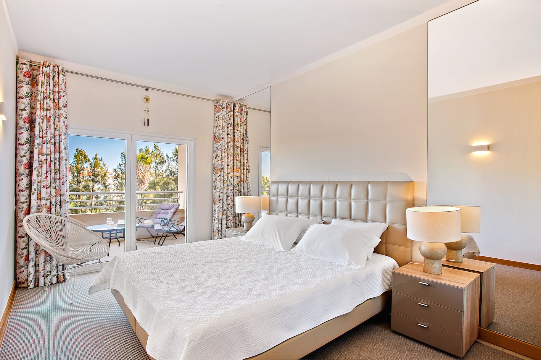 Bedroom with double bed, patterned curtains, and balcony access