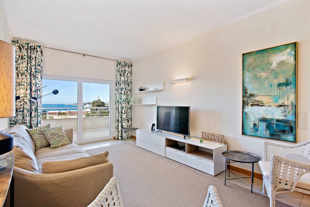 Living room with sofa, TV, and balcony access