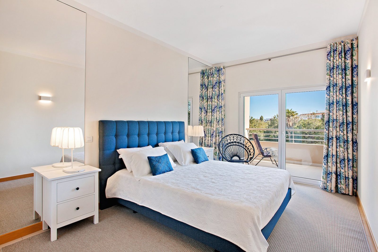 Bedroom with blue upholstered headboard, sea view, and balcony access