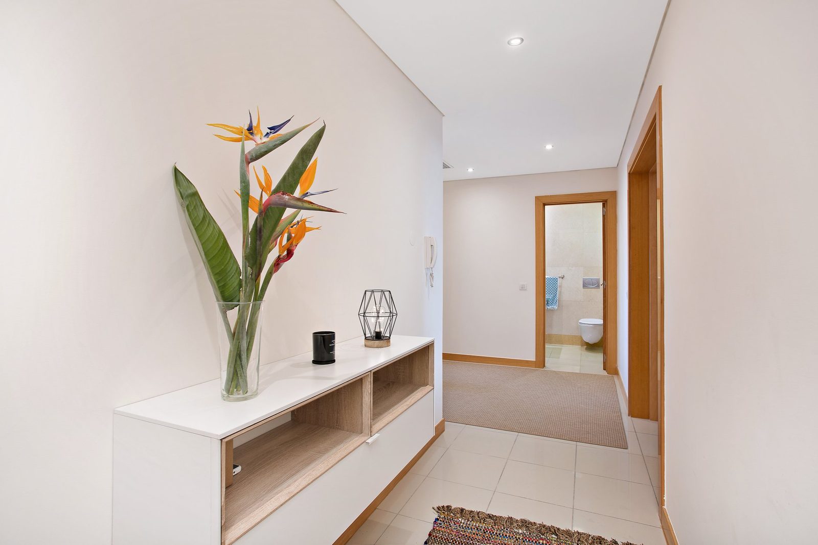 Hallway with decorative console table and doors leading to the bedrooms and bathroom