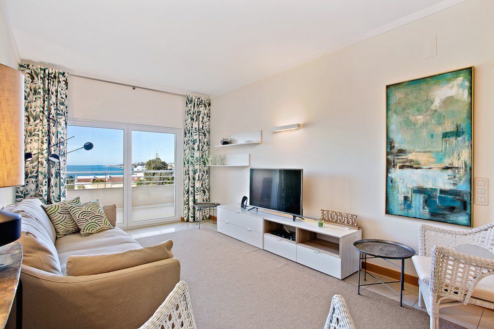 Living room with sofa, TV, and balcony access