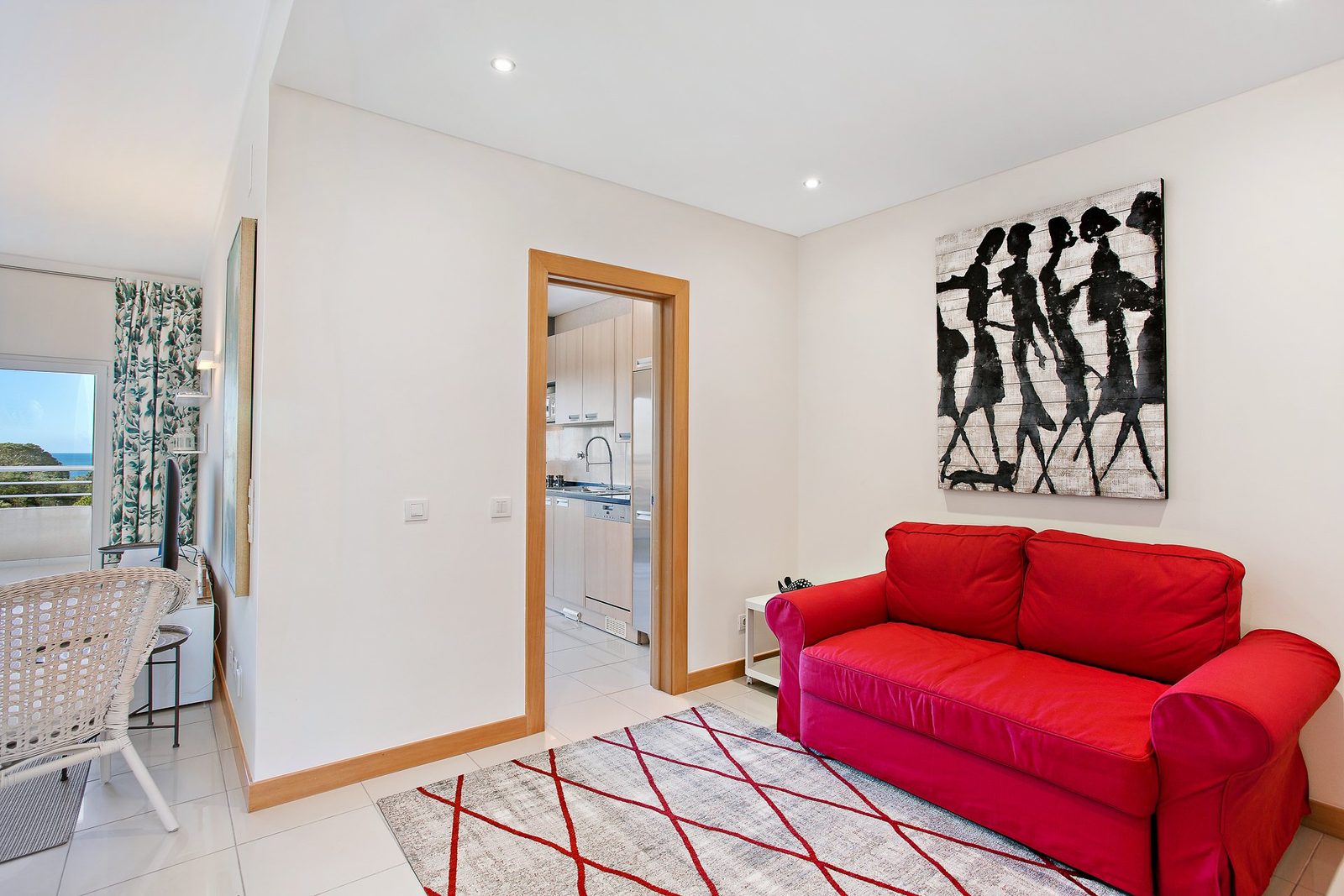 Living room with red sofa bed, sea view, and kitchen access