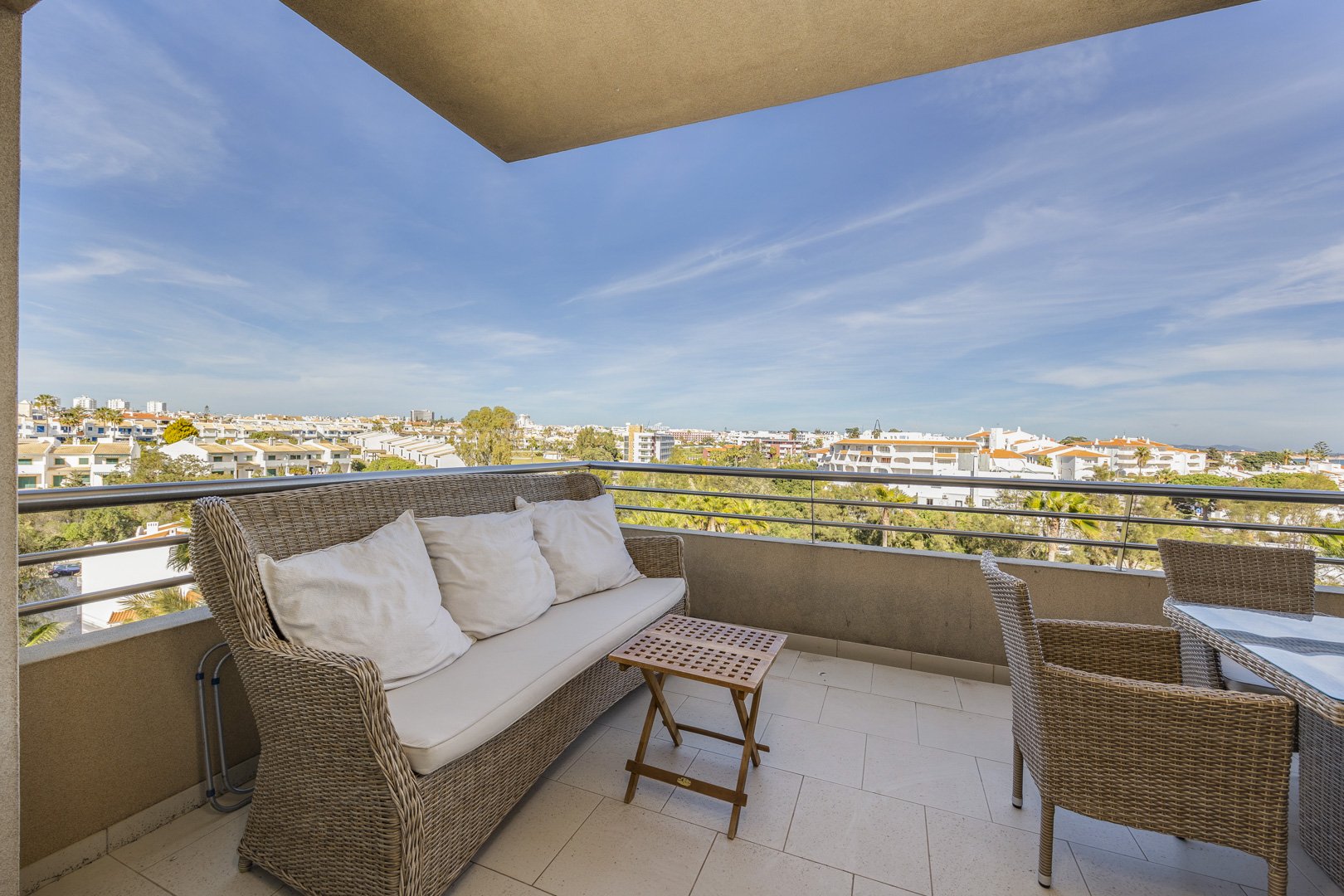 Balcony lounge area with sofa, chairs, and rooftop view