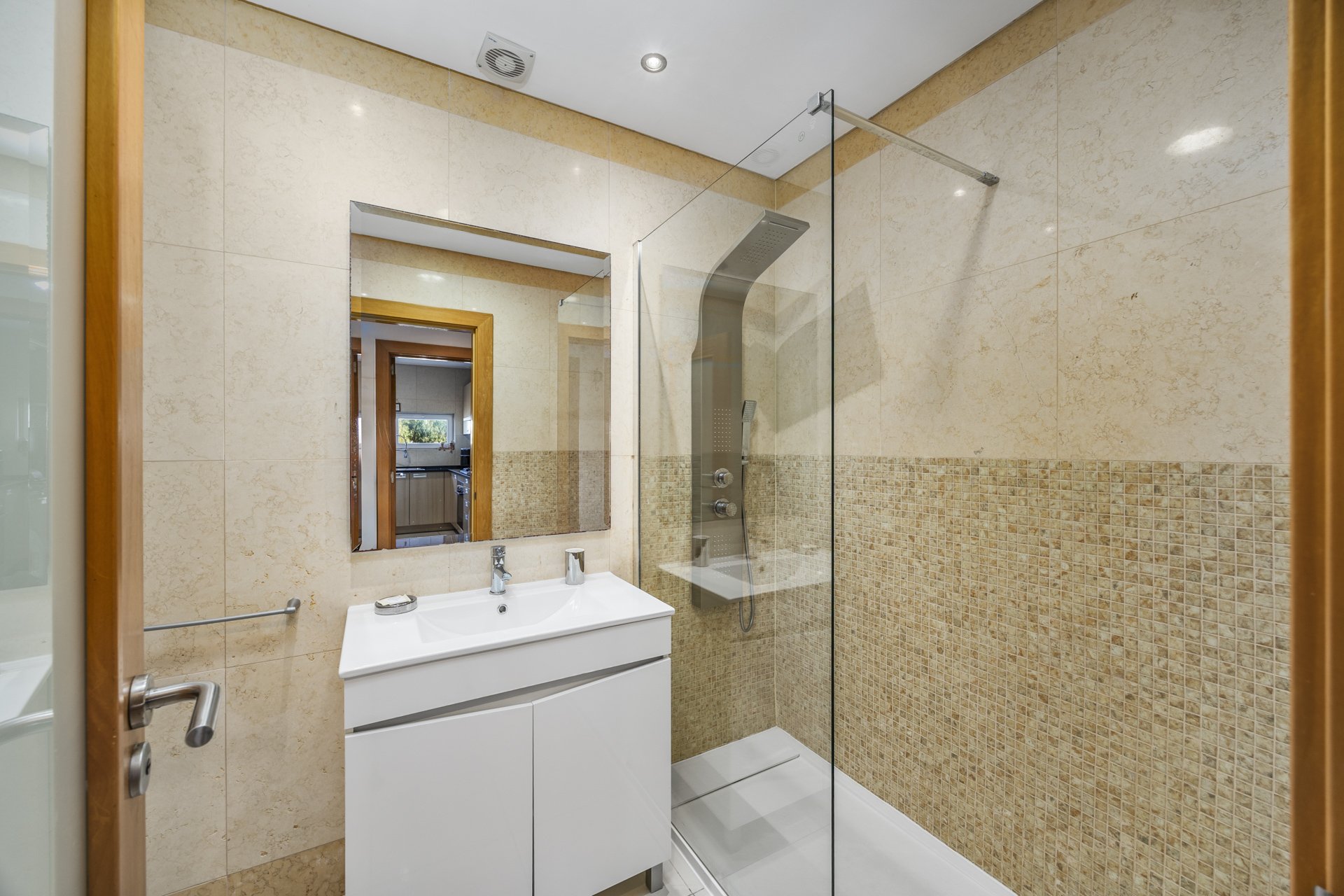 Bathroom with vanity sink, mirror, and corner glass shower
