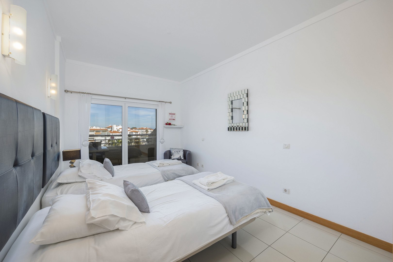 Bedroom with beds pushed together, decorative wall mirror, and balcony access