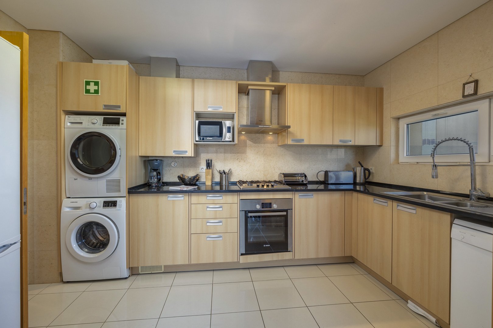 Kitchen with stacked washer-dryer, oven, and hob