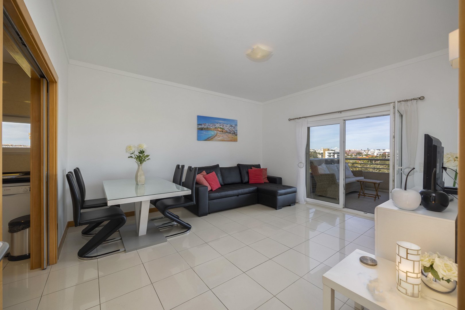 Living and dining area with dining table, black sofa, and TV