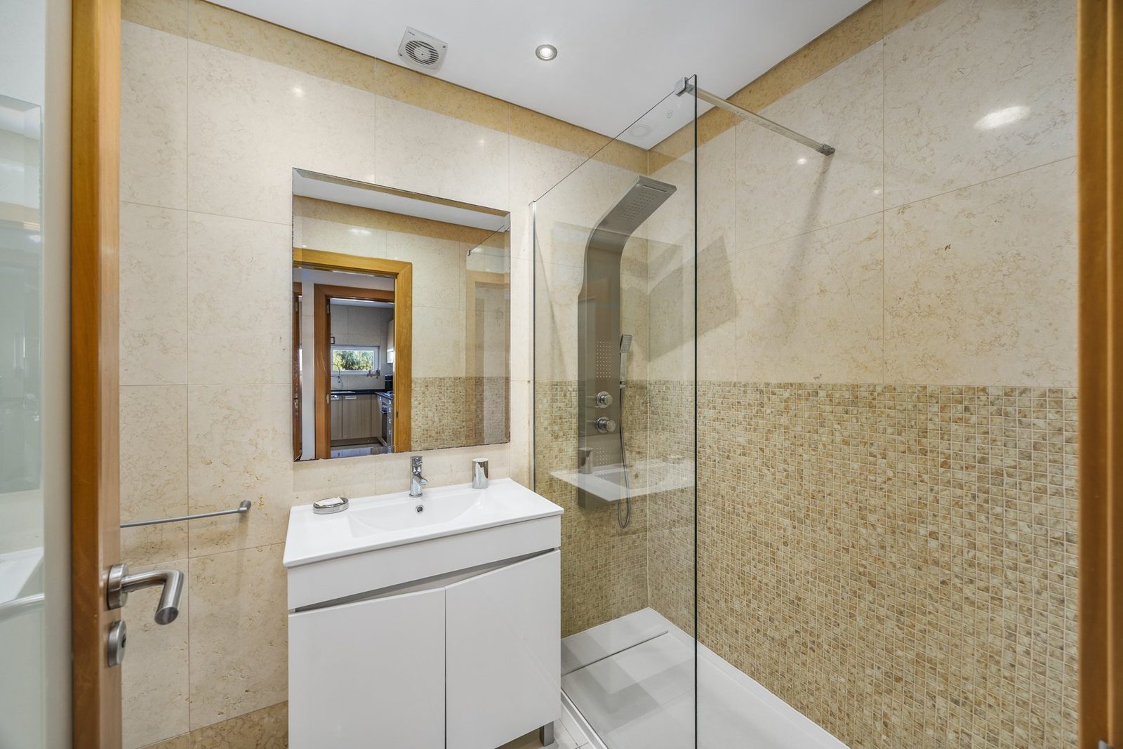 Bathroom with vanity sink, mirror, and corner glass shower