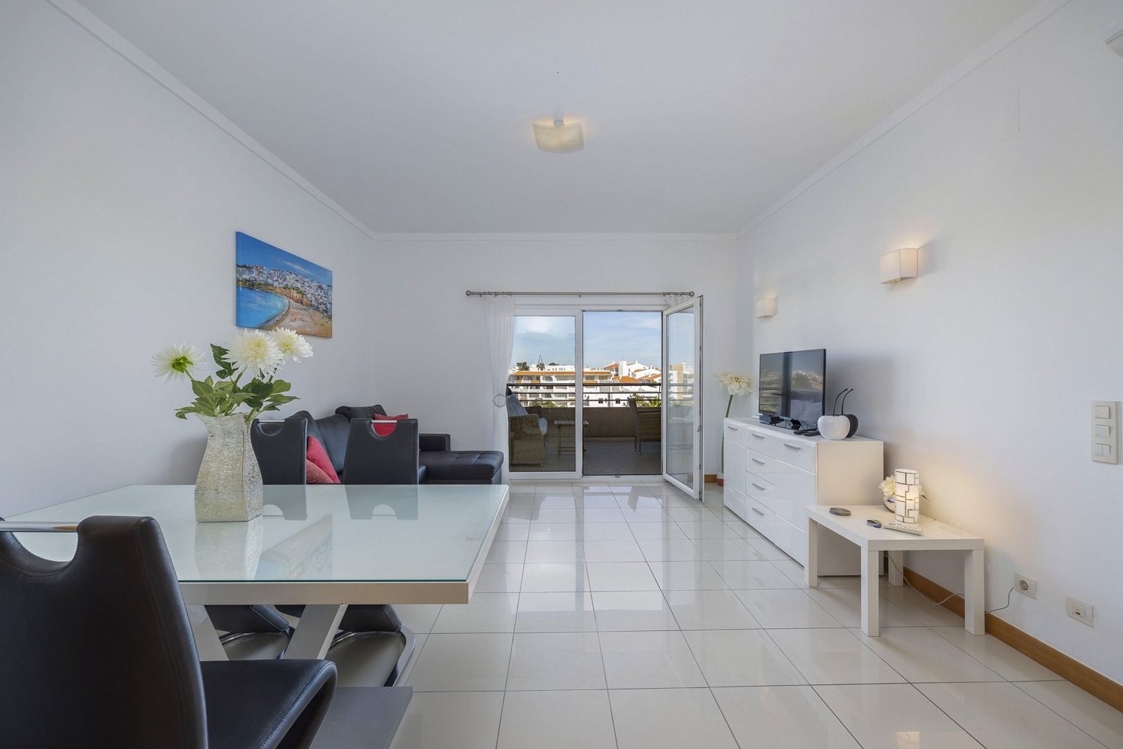 Living and dining area with dining table, sofa, and balcony access