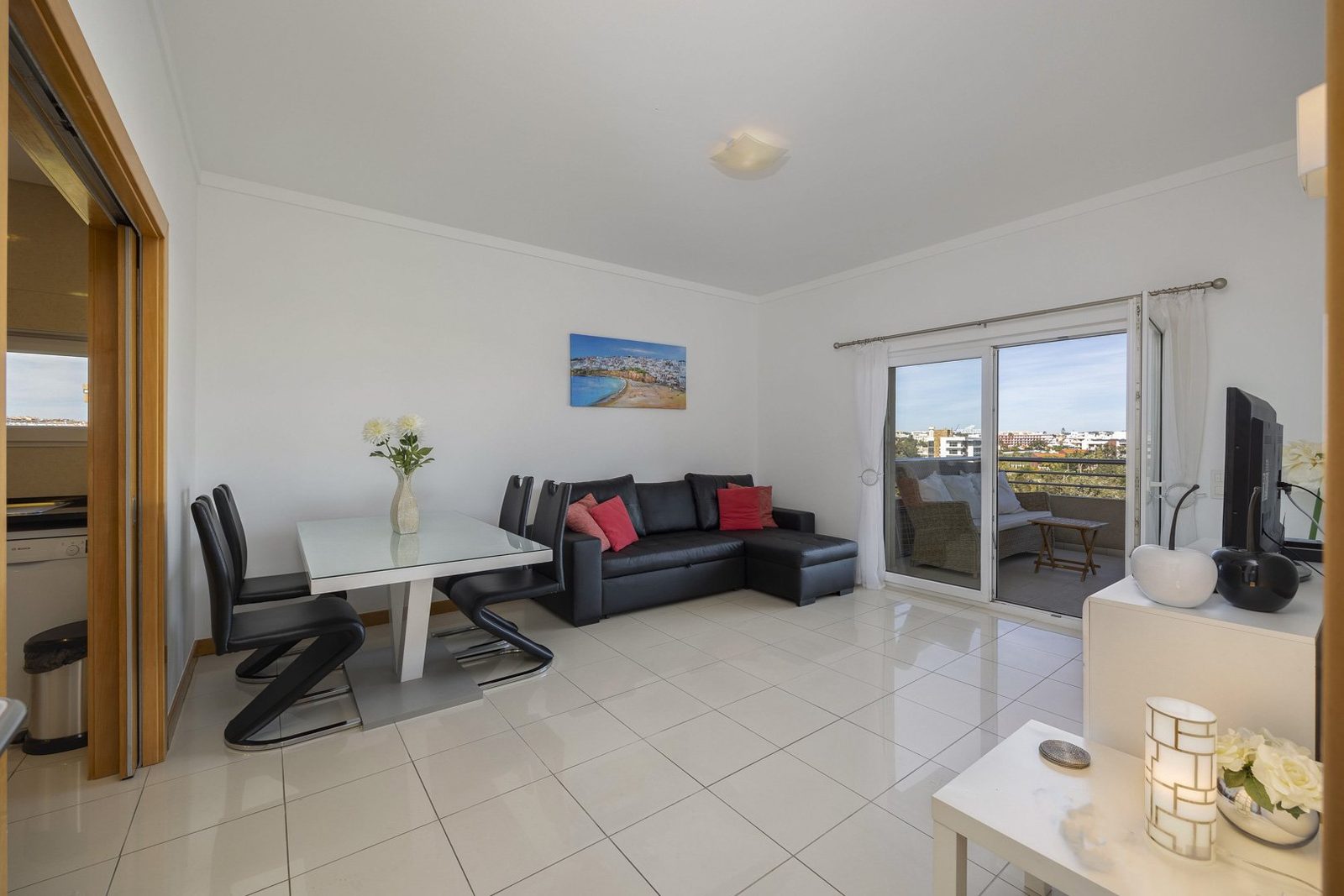 Living and dining area with dining table, black sofa, and TV