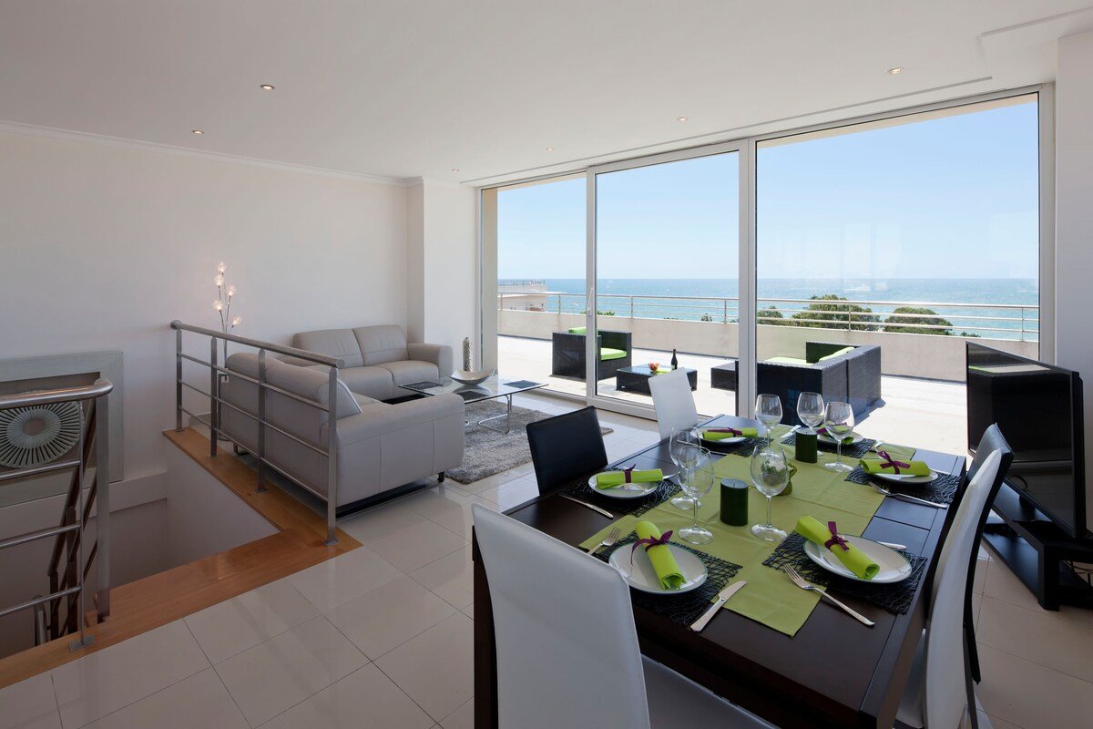 Open-plan living and dining area with sea-view balcony access