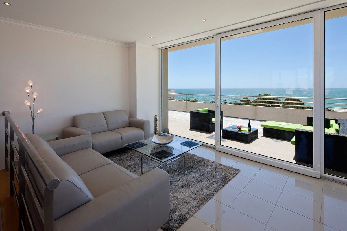 Living room with sofas and glass coffee table opening onto the terrace