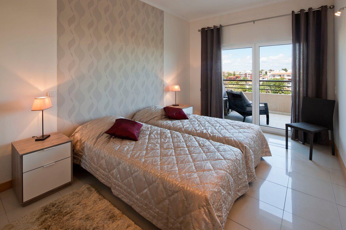 Twin bedroom with patterned feature wall and balcony access
